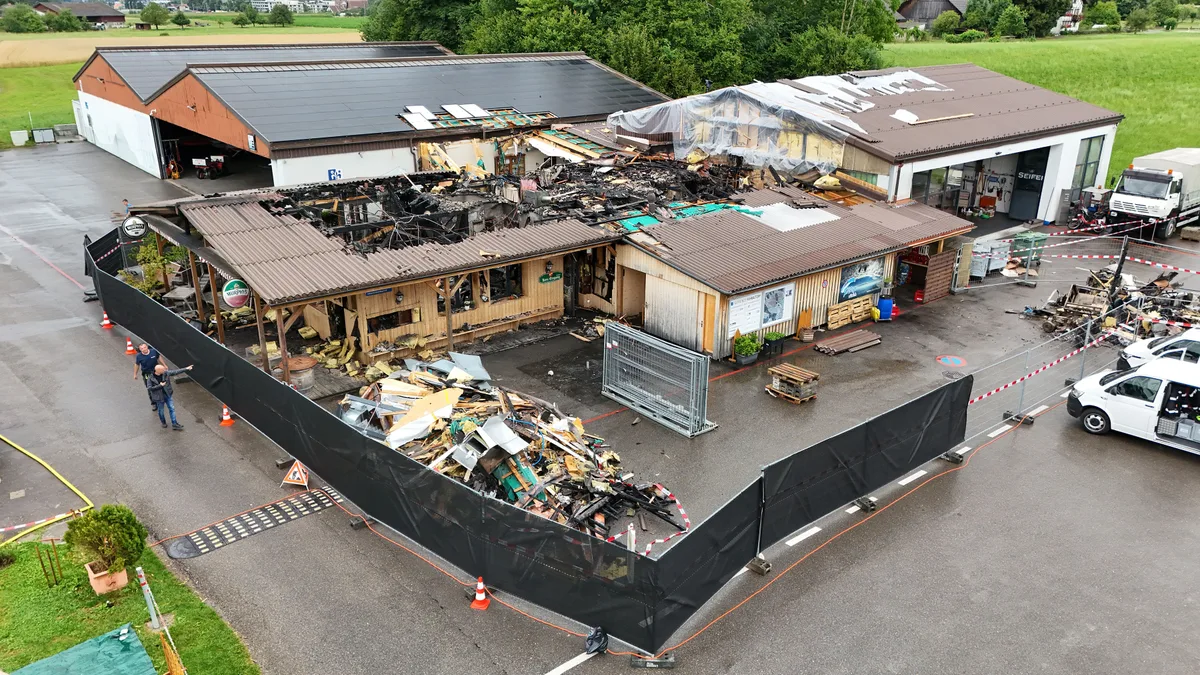 Um die Brandruine steht nun ein Zaun mit schwarzem Sichtschutz. Nachzug zum Brand auf dem Flugplatz Speck in Fehraltorf.